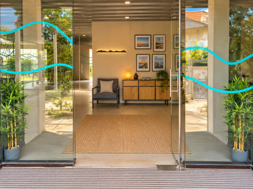 Entrada moderna del apartamento Holibai Baiona con puertas de cristal, vista a terraza, muebles de madera y acceso al jardín