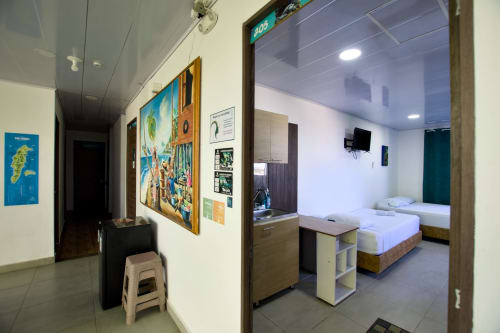 Apartamento 205 en Vamos pa San Andrés Isla con camas gemelas, vista al mar, TV, AC, escritorio y decoración caribeña colorida en la entrada