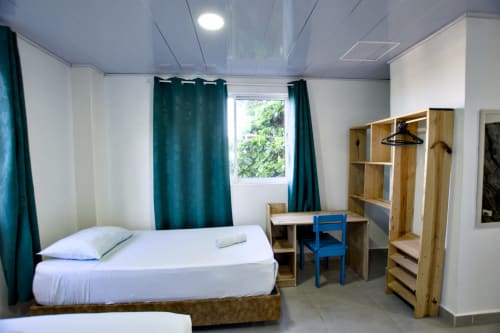 Habitación luminosa en Vamos pa San Andrés Isla con cama, escritorio, almacenamiento de madera, cortinas turquesas y vista al mar