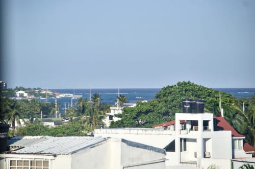 Vista del apartamento frente a playa en San Andrés con Mar Caribe, palmeras tropicales y edificios costeros