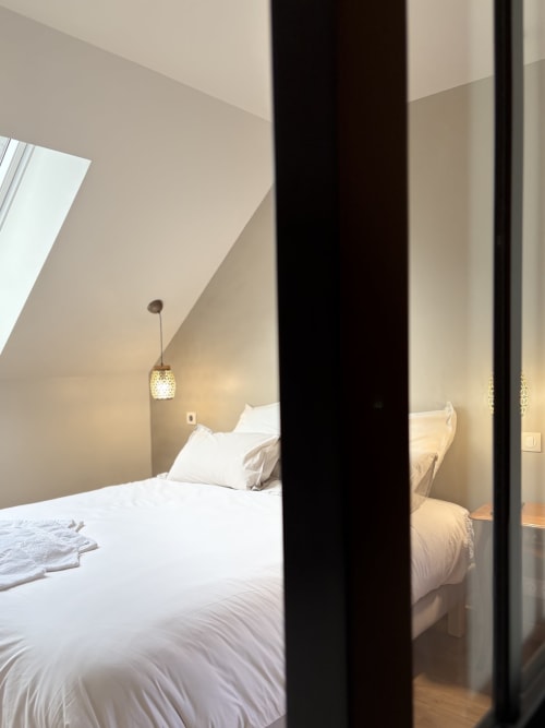 Chambre moderne à La cour des Agapanthes : lit blanc, suspension luminaire et cloison noire