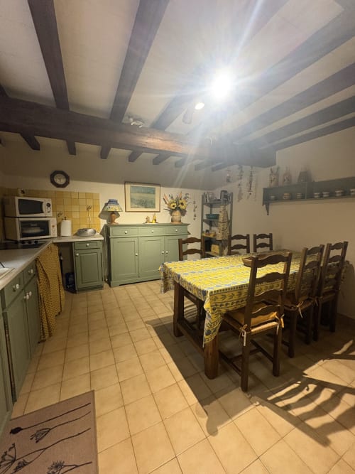 Coin cuisine-salle à manger charmant à Arles avec poutres apparentes, nappe à motifs jaunes, chaises en bois rustique
