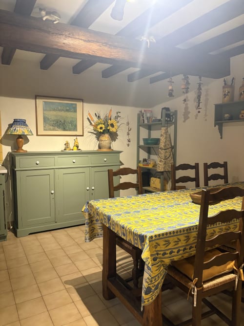 Salle à manger provençale à Arles avec nappe jaune, chaises en bois et buffet vert