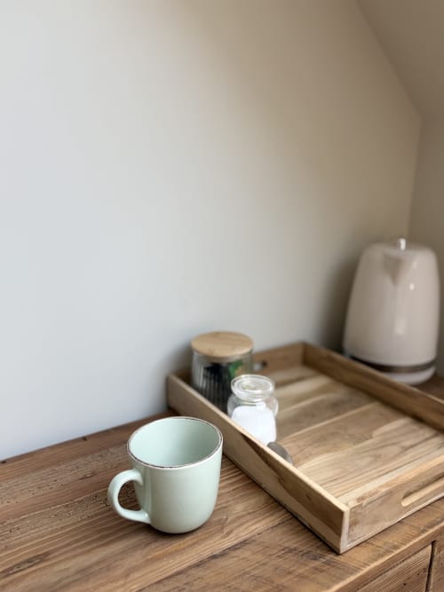 Table de chevet minimaliste à La cour des Agapanthes avec tasse blanche, plateau en bois et diffuseur crème