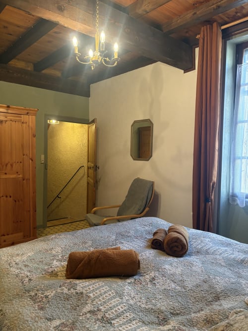 Salle de spa à Arles avec lit de massage, serviettes, carrelage en pierre et poutres en bois