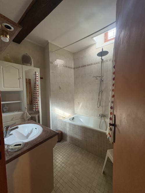 Salle de bain moderne dans un gîte à Arles avec lavabo blanc, douche carrelée et pommeau de douche pluie
