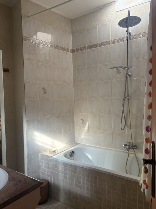 Salle de bain moderne avec baignoire, douche à effet pluie et paroi vitrée à l'hôtel d'Arles