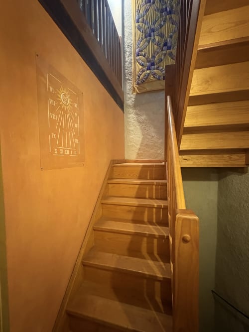 Escalier en bois d'une maison arlésienne avec cadran solaire gravé sur mur orange et tapisserie décorée au plafond