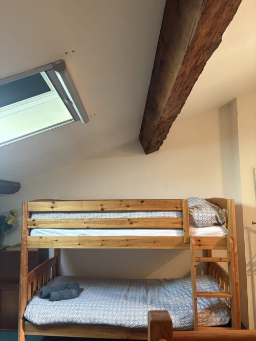 Lit superposé en bois avec matelas dans chambre lumineuse avec poutre apparente à la Conciergerie Maurin, Arles