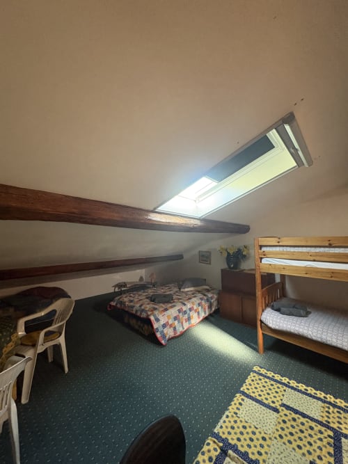 Chambre mansardée à Arles avec puits de lumière, poutres apparentes, lit double, lits superposés et tapis à motifs jaunes