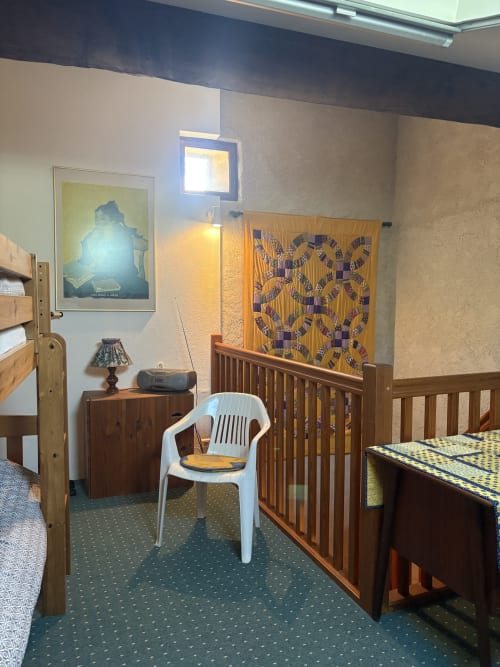 Chambre de la maison d'hôtes à Arles avec meubles en bois, chaise blanche, tapisserie motifs et œuvres d'art
