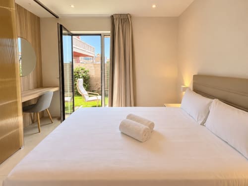 Habitación moderna y accesible del hotel Holibai en Baiona con vistas al jardín, escritorio y puertas que abren a la terraza