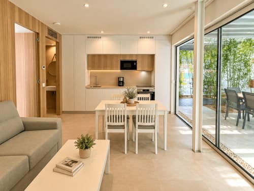 Interior accesible del apartamento Holibai con sala abierta, cocina americana, comedor y vistas al jardín en Baiona
