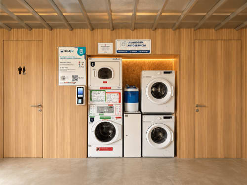 Lavandería de autoservicio con lavadoras y secadoras en el apartamento Holibai de Baiona, España
