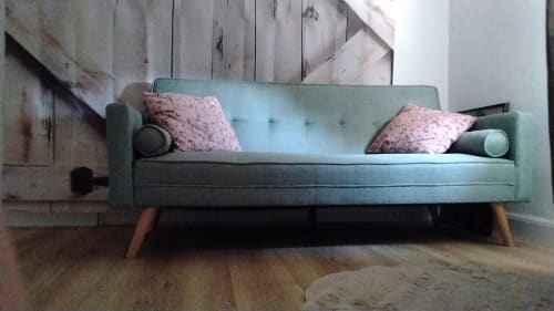 Sofá verde menta moderno com almofadas rosa e pés de madeira na sala de estar do apartamento Maison de Barlest