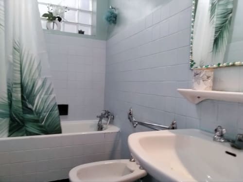 Banheiro moderno na Maison de Barlest com azulejos brancos, pias duplas, banheira, espelho e decoração botânica
