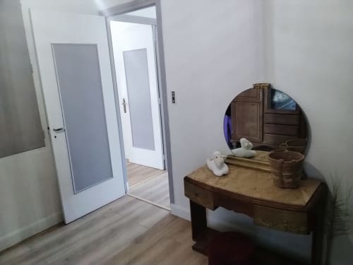 Corredor luminoso no apartamento Maison de Barlest com portas brancas, escrivaninha de madeira, espelho redondo e piso em madeira clara