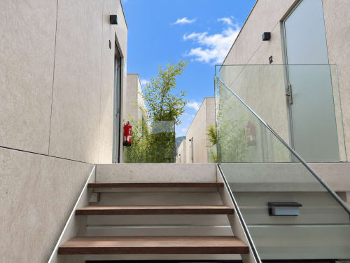 Escalera moderna entre edificios contemporáneos del hotel apartamento Holibai en Baiona con vistas a la ciudad y cielo azul
