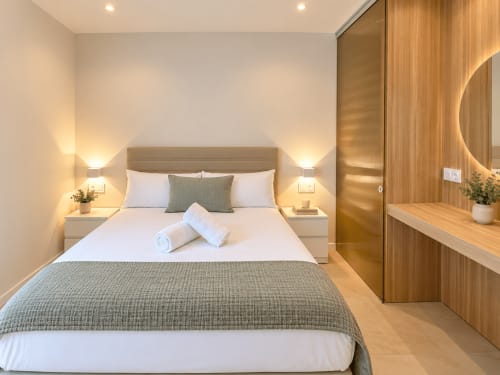 Habitación moderna en los apartamentos Holibai de Baiona con cama doble, armarios de madera e iluminación ambiental
