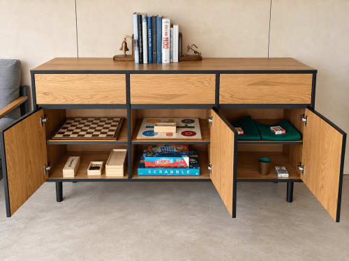 Moderno gabinete de almacenamiento de madera con cajones en apartamento Holibai, exhibiendo juegos de mesa y libros en estante superior