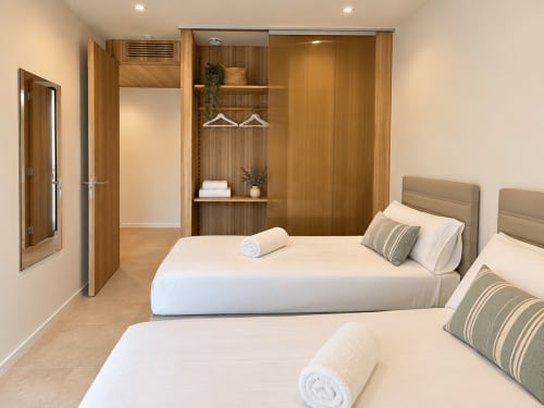 Dormitorio doble moderno en ModulSenses Baiona con armario empotrado de madera, decoración neutral y ropa de cama blanca