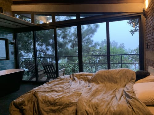 Cama sin hacer en loft Queen con ventanales panorámicos con vista a las montañas del hotel Sento SanMa, San Mateo Rio Hondo