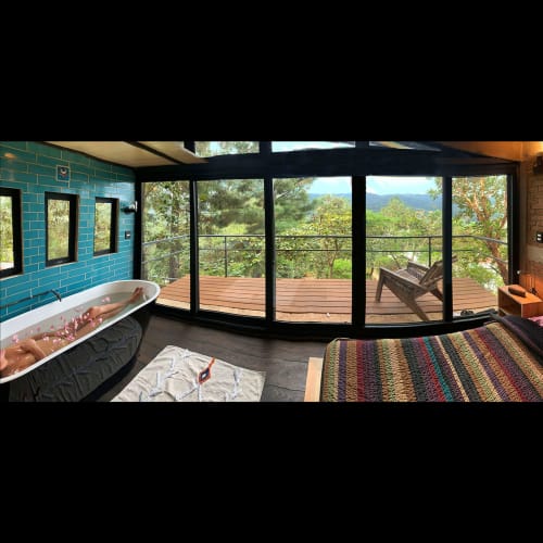 Baño de lujo en Sento SanMa con azulejos color turquesa, bañera independiente y vistas a las montañas desde ventanales