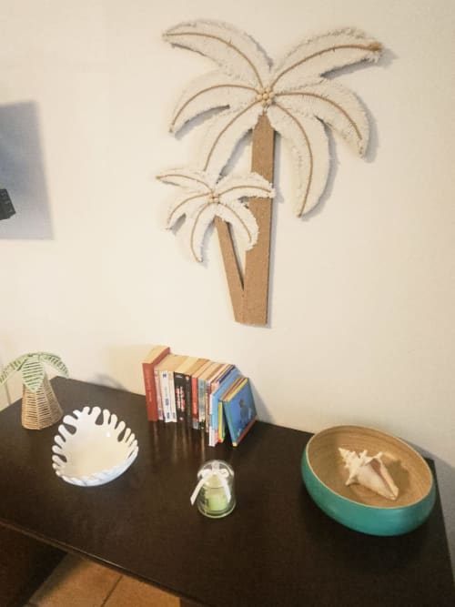 Décoration tropicale à Ti Oasis : peinture palmiers, livres colorés et bols décoratifs sur étagère noire