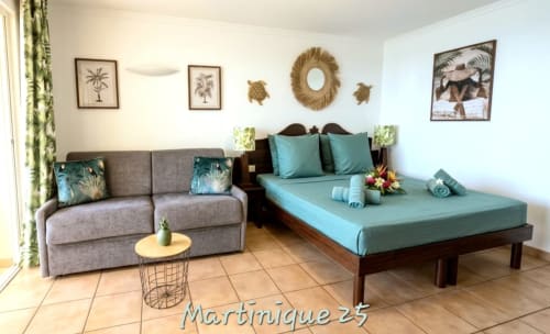 Chambre tropicale à Ti Oasis Martinique avec lit turquoise, canapé, art palmette et décoration insulaire