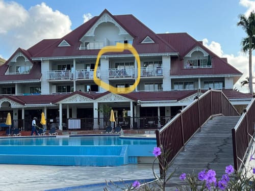 Hôtel Ti Oasis à Sainte-Luce : vue sur piscine, toits en terre cuite, garde-corps blanc, bassin bleu et palmiers tropicaux