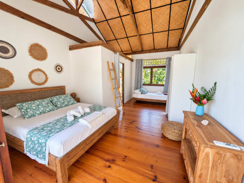 Chambre Ta'urua au Fare Tihi Moana à Tumaraa : lit en bois, plafond tressé, décor tropical et banquette fenêtre