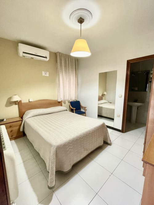 Luminosa habitación doble en Hotel JM El Emigrante de Villanueva de la Serena con cama de madera, aire acondicionado y baño privado