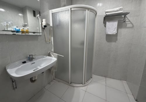Baño moderno con cabina de ducha, lavamanos y toallero blanco en Hotel JM El Emigrante, Villanueva de la Serena