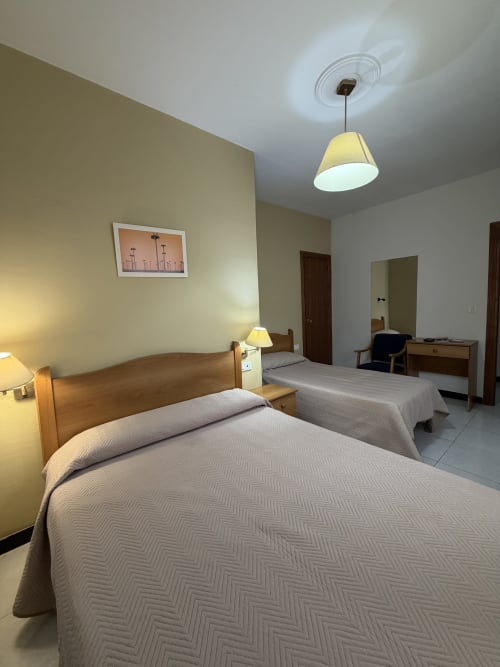 Habitación doble del Hotel JM El Emigrante con dos camas, muebles de madera e iluminación de lámparas colgantes en Villanueva de la Serena