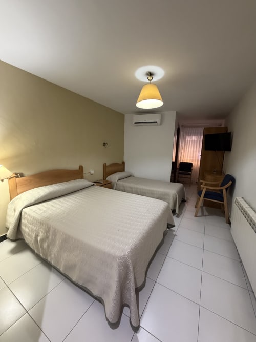 Habitación doble con cama extra en Hotel JM El Emigrante, Villanueva de la Serena, con dos camas y comodidades modernas