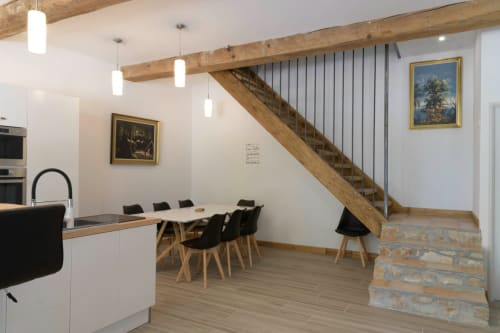 Modern open-plan kitchen and dining area at Domaine Le Piboul with wooden beams, staircase, and contemporary furnishings