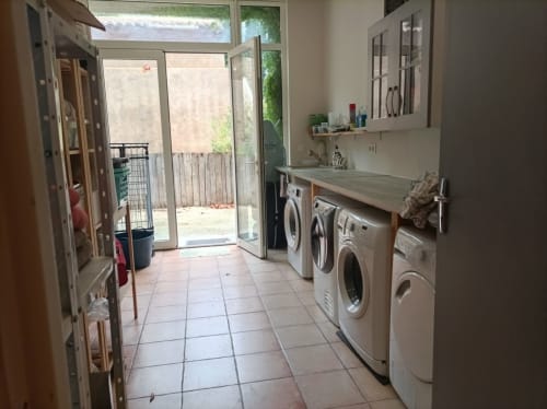 Laundry room at Domaine Le Piboul with washing machines, sink, and doors opening to patio in Fontcouverte