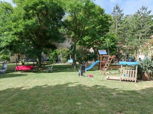 Spacious garden at Domaine Le Piboul with playground, lounge chairs, and mature trees in Fontcouverte