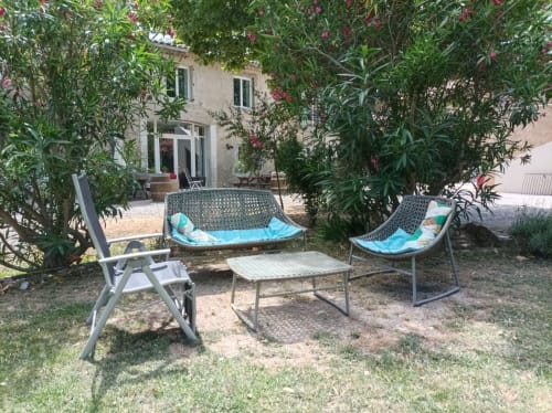 Shaded garden seating area with loungers and table at Domaine Le Piboul B&B in Fontcouverte, France