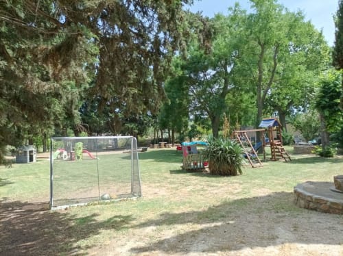Outdoor playground area at Domaine Le Piboul in Fontcouverte with soccer goal, slides, and climbing equipment among tall