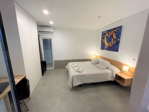 Habitación moderna en Hostal Fornet Altea con cama doble, mesillas de madera, paredes blancas y obra de arte contemporáneo en Altea,