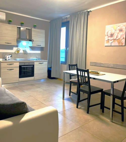 Appartamento moderno con cucina-sala da pranzo a La Piazzetta Signa, mobili in legno chiaro, tavolo da pranzo, sedie nere e vista giardino