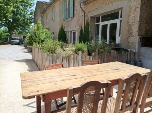 Outdoor dining table and chairs at Domaine Le Piboul in Fontcouverte, with rustic stone buildings and Mediterranean gardens
