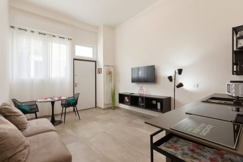 Monolocale moderno presso LM Apartments Pavia con TV, zona living e angolo cottura in uno spazio luminoso e contemporaneo