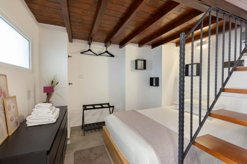 Camera moderna agli LM Apartments Pavia con travi in legno, letto matrimoniale, ringhiera in metallo e arredi scuri