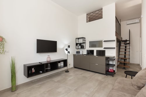 Moderna sala living presso gli Apartments LM di Pavia con TV, angolo cottura e scala per la mezzanine