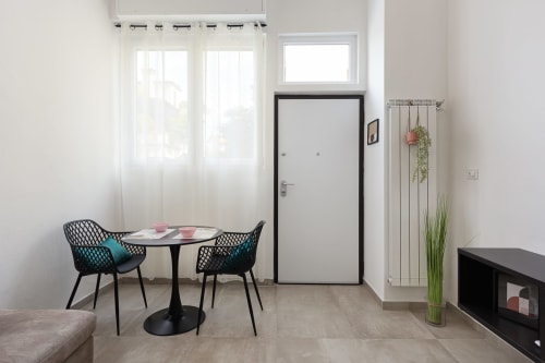 Moderno monolocale presso LM Apartments Pavia con tavolo da pranzo, sedie nere e ampie finestre con vista sulla città