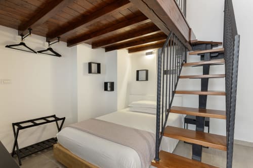 Camera da letto in stile loft moderno con travi in legno, scala in metallo e pareti bianche presso LM Apartments Pavia
