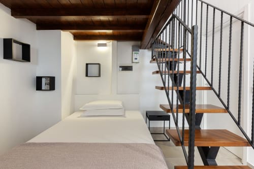 Camera da letto moderna a Pavia con scala in legno, letto bianco e vista sulla città