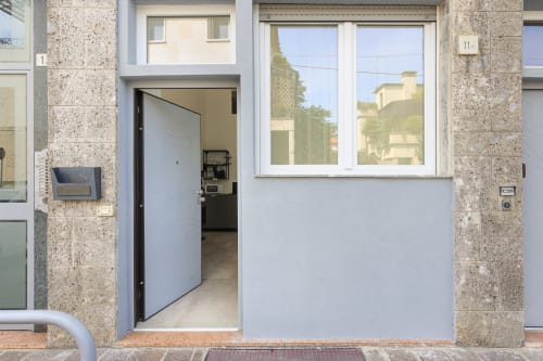 Ingresso moderno degli LM Apartments Pavia con porta in vetro, ampie finestre e facciata in pietra a Pavia, Italia